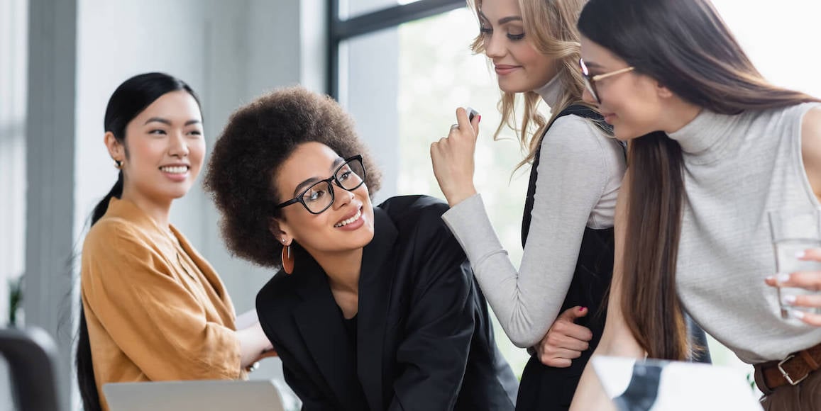 A young group of busy marketers gathered at a table and looking at a computer as they search for conversion optimization tips.