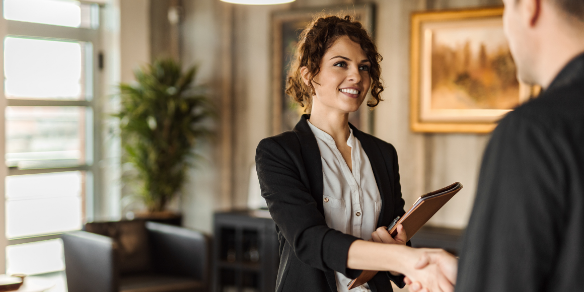 smiling woman wearing a suit in office and shaking hands with man