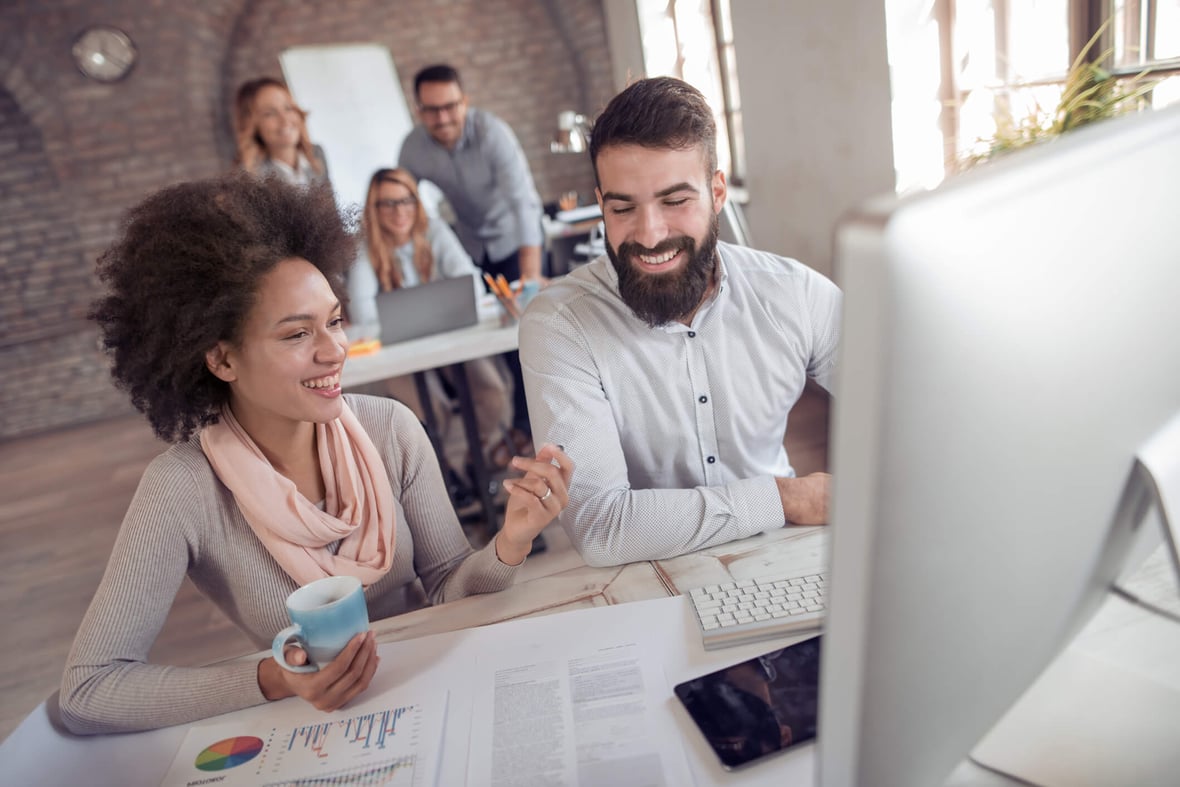 Two marketers at a computer working on their paid media campaign