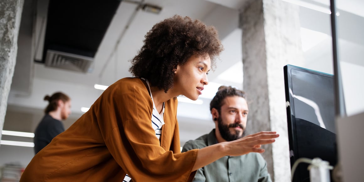 Person looking intently at a computer monitor, advising another user about what is on the screen.  