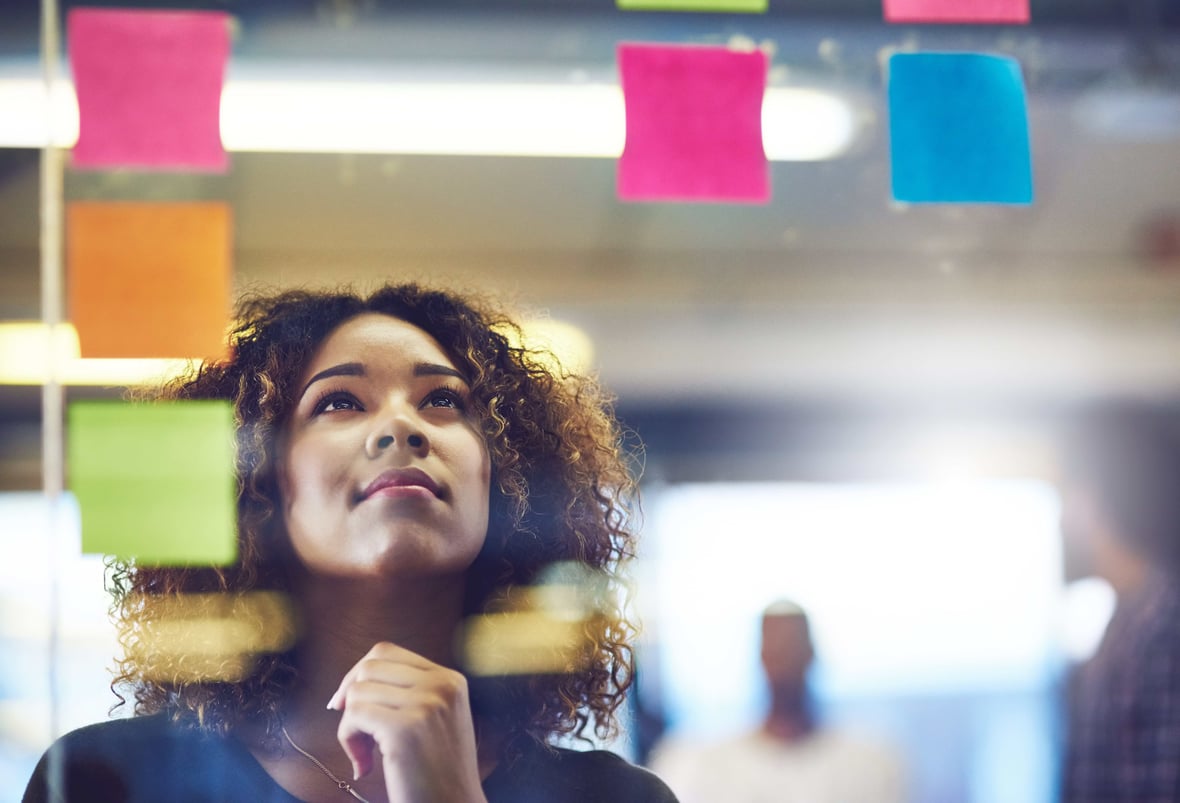 A person plans their inbound marketing strategy, looking at post-it notes attached to a glass window. 