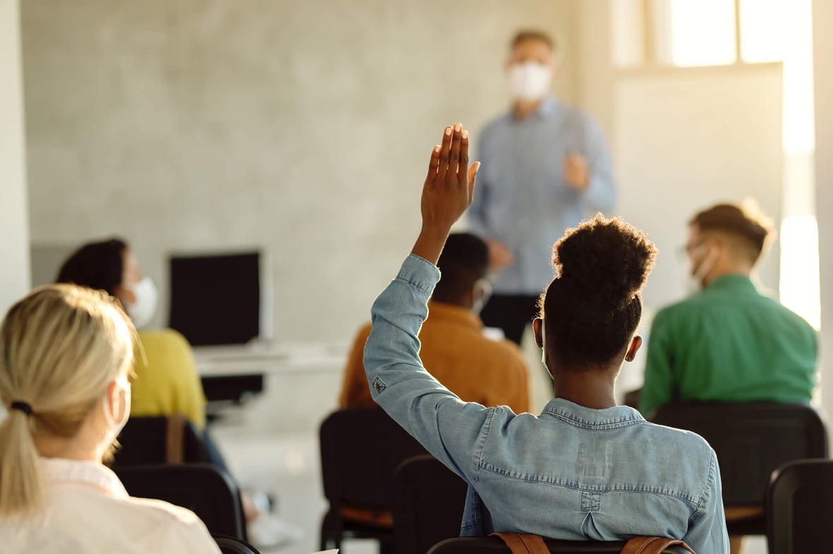 students in classroom raising hand