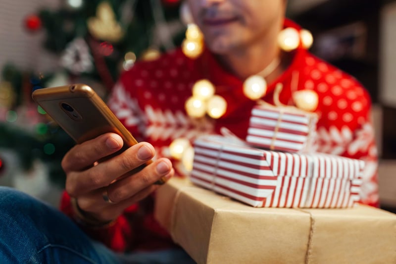 A person holding a phone and some Christmas presents