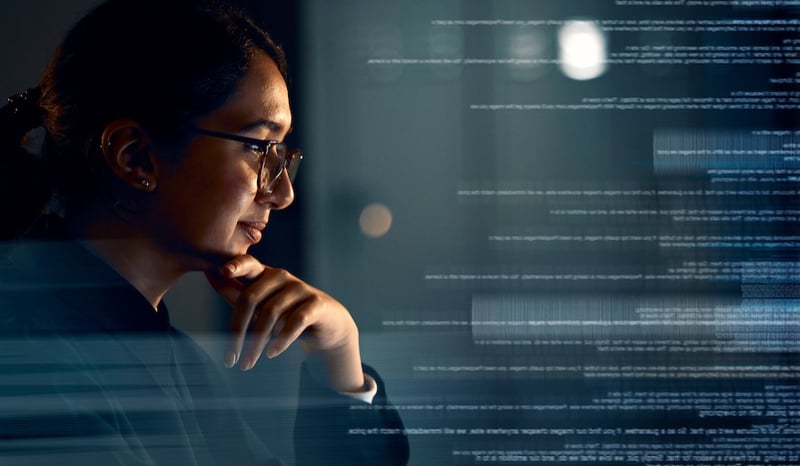 Woman working on a laptop with hologram overlay for database review at night