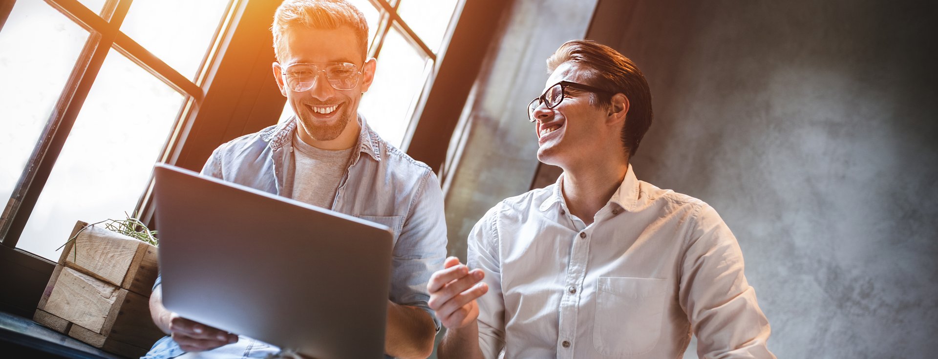 Two employees smiling and working on a laptop