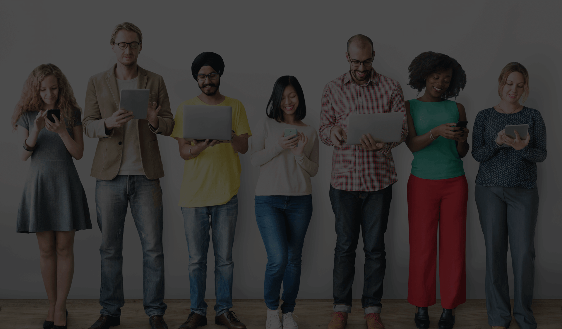 Seven people standing in a line on their devices