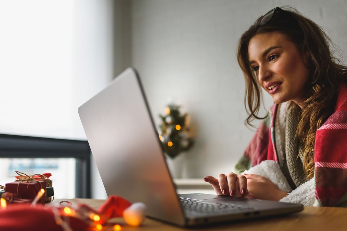 Women looking at her laptop with Holiday lights in the background