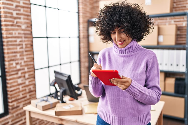 Young woman holding a red tablet reviewing her BFCM marketing planning checklist