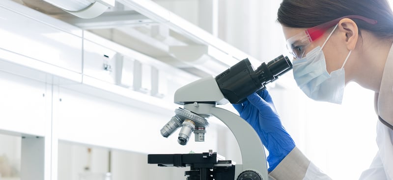 Arcmed Banner Image Scientist looking through microscope