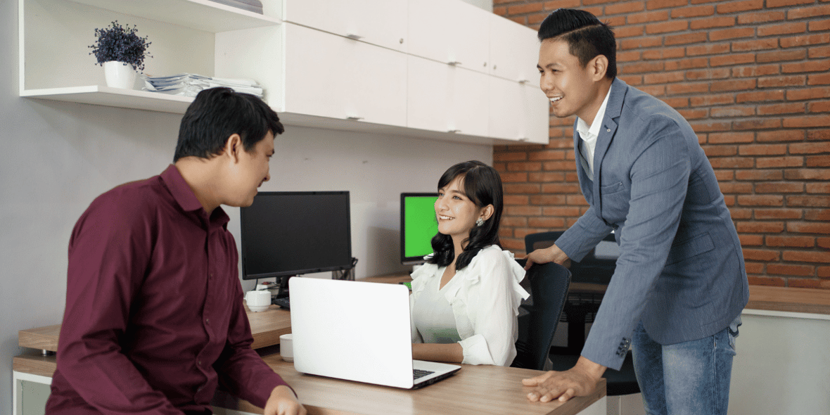 Three coworkers talking at a desk