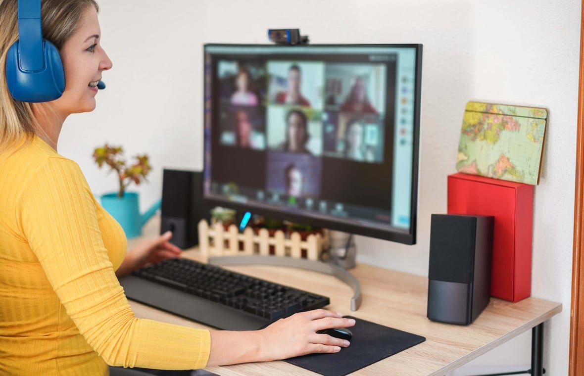 professional woman in home office video chatting with remote teammates on desktop computer