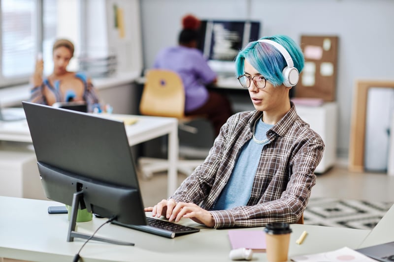 Man with blue hair working in office to explore user experience pitfalls on Shopify website