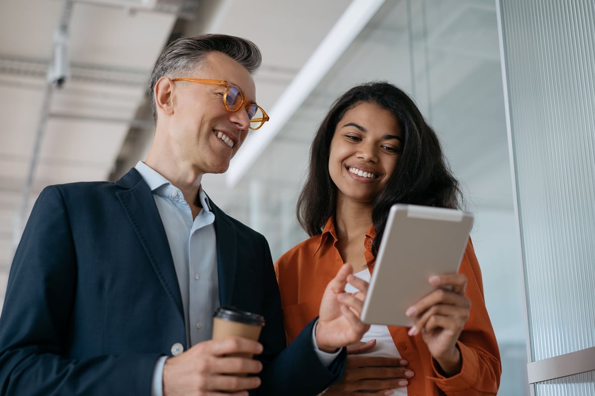 Two marketers looking at a tablet and smiling in an office