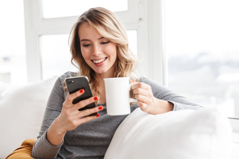 Woman looking at her phone while holding a cup of coffee