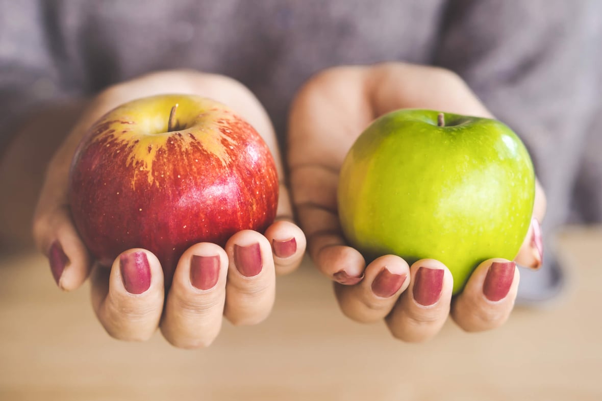 Image of two hands holding two apples of different colors, a red one and a green one