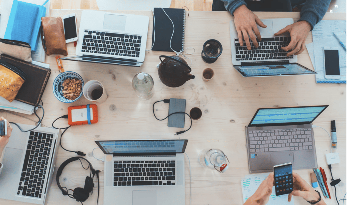 Group of laptops and office items on a table as seen from above