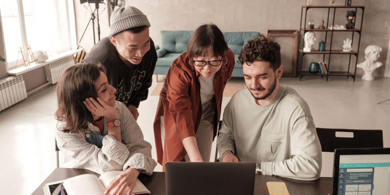 Four marketers looking at a laptop and smiling