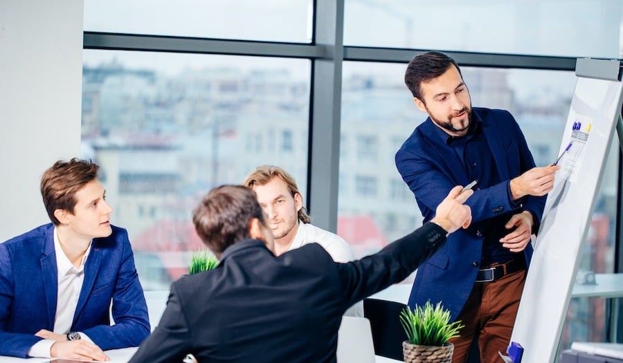 Man showing information on a board to his colleagues at a business meeting