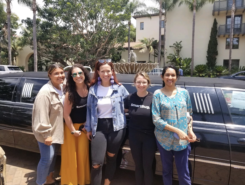 Five marketers smiling together in front of a limousine, with several of them wearing SmartBug Media t-shirts