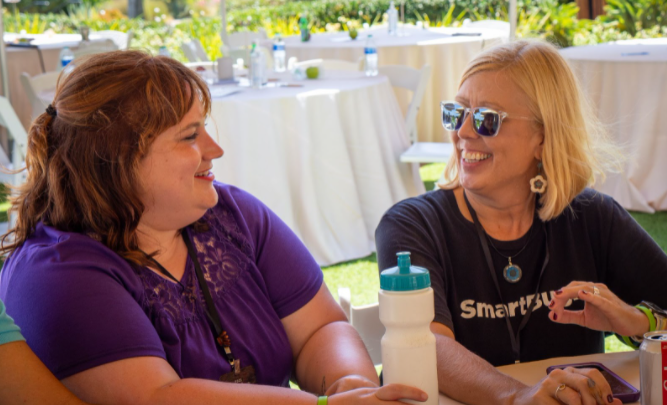 Two creatives looking at each other and laughing on a table