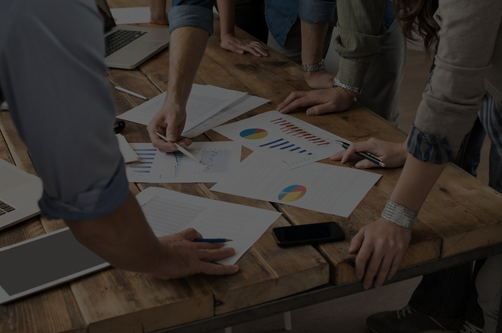 People standing around table looking at printed charts