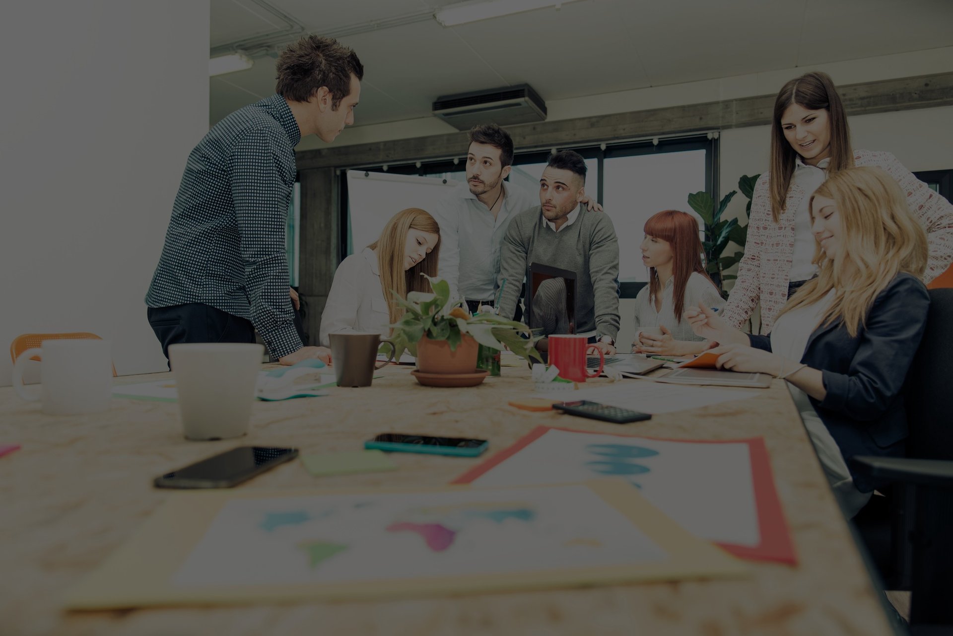 Employees standing and sitting around a workspace