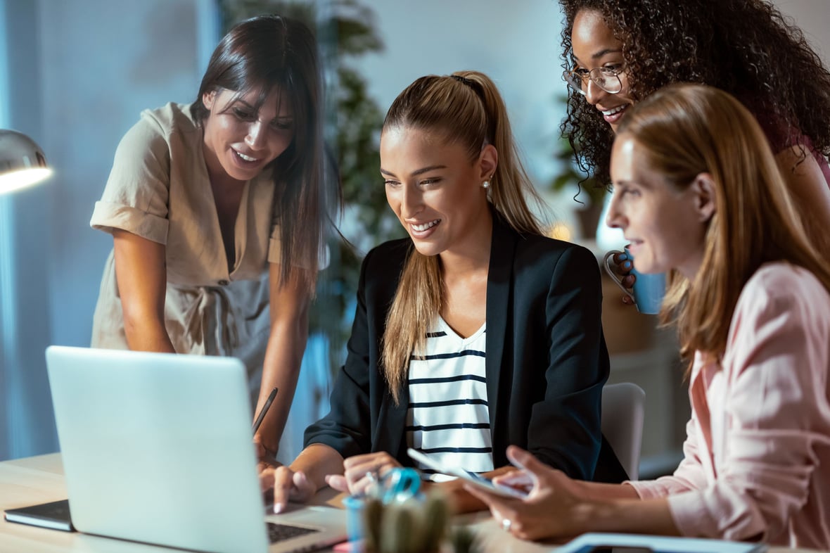 4 marketers looking at a laptop while smiling