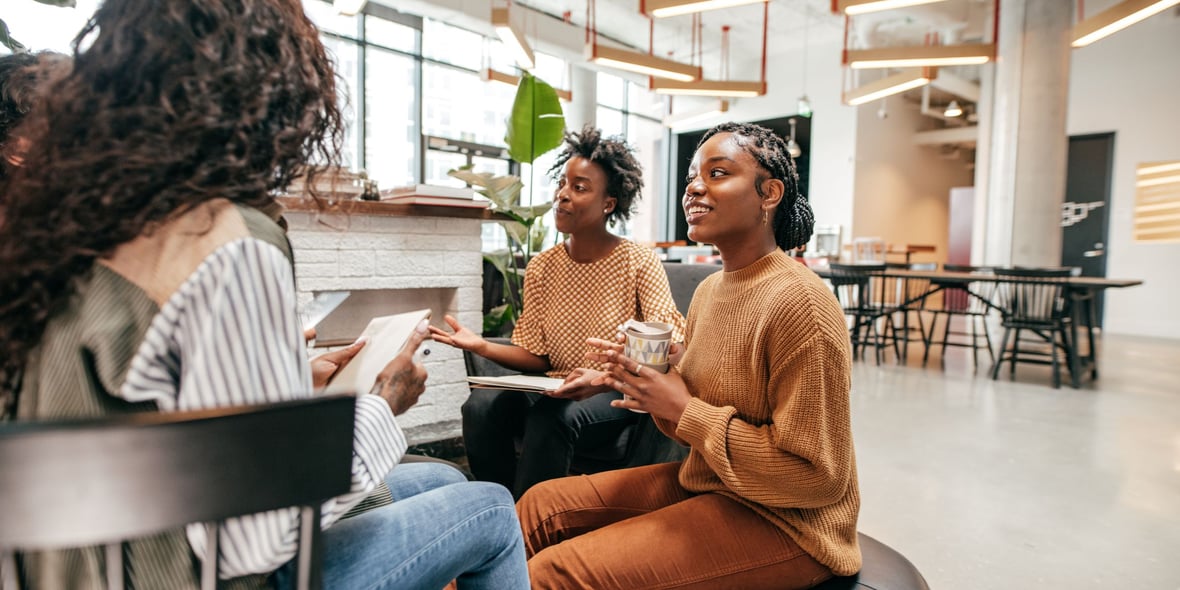 3 women discussing with each other at a co-working space