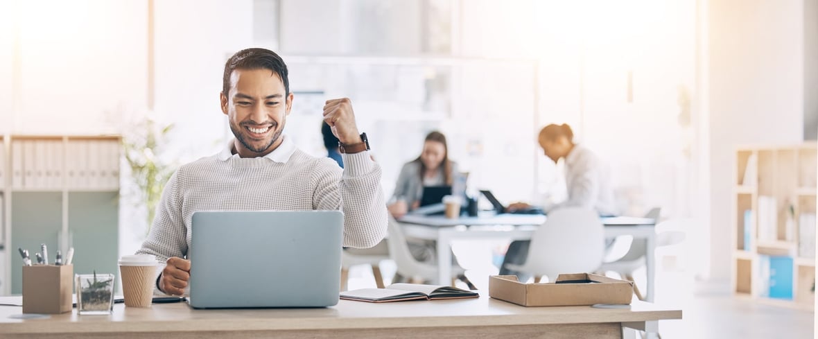 A man smiling while looking at his laptop