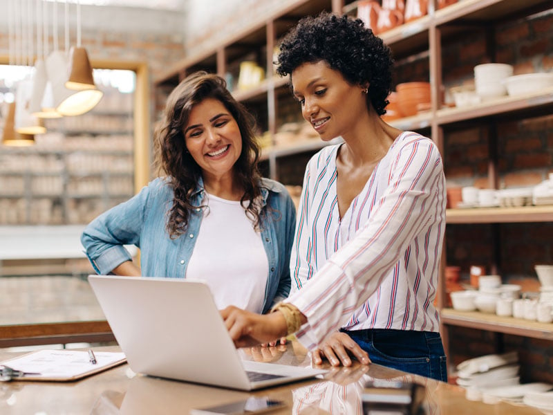 Two women in a retail space looking at a laptop