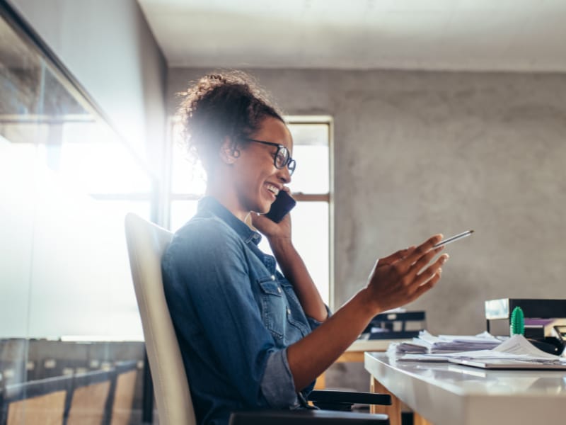 woman laughing on cell phone at her desk